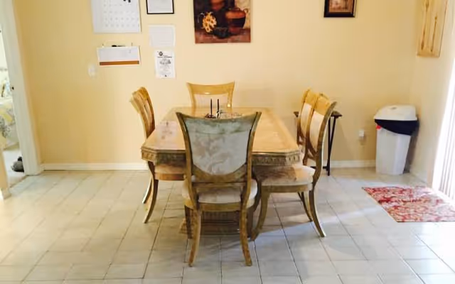 A wooden dining table with six upholstered chairs in a bright dining room.