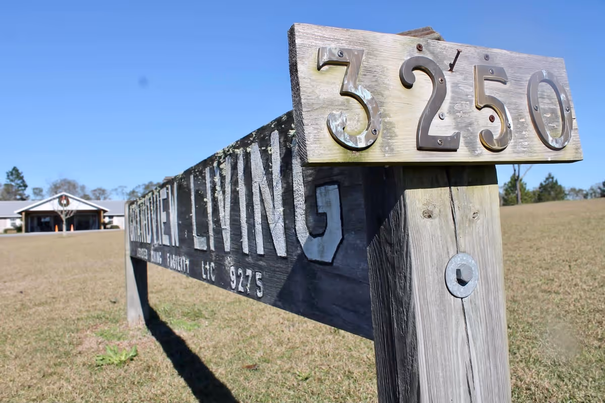 Wooden address sign reading '3250' and 'Grandview Living' in front of a single-story building on a grassy lawn.