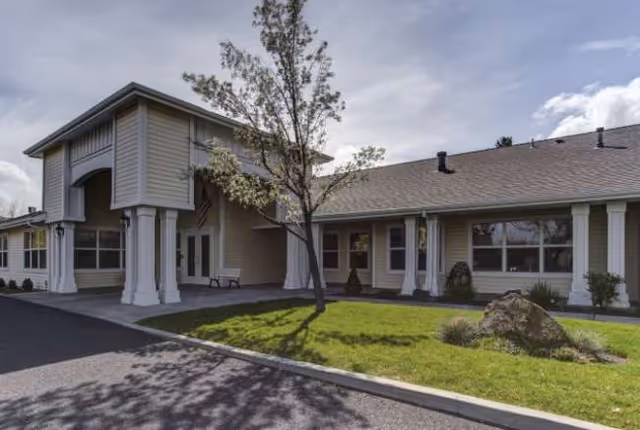 Exterior view of Terrango Glen Senior Care entrance with lawn, tree, and landscaping.