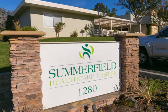 Stone-framed entrance sign reading "SUMMERFIELD HEALTHCARE CENTER 1280" in front of a single-story building.