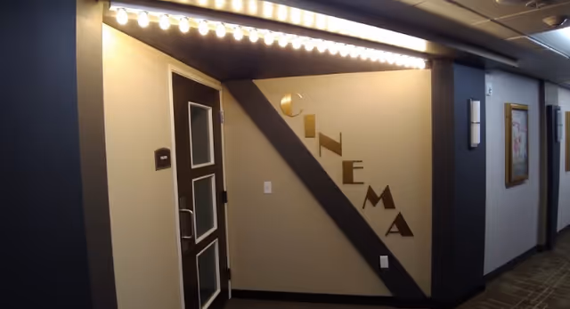 Interior hallway showing a marquee-lit entrance labeled "CINEMA" with a door featuring frosted glass panels.