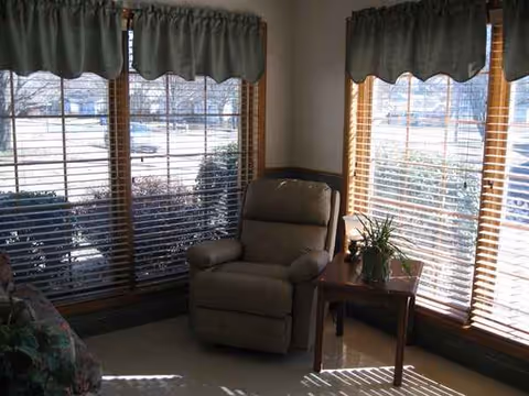 Cozy living area with a recliner, small table, and large windows.