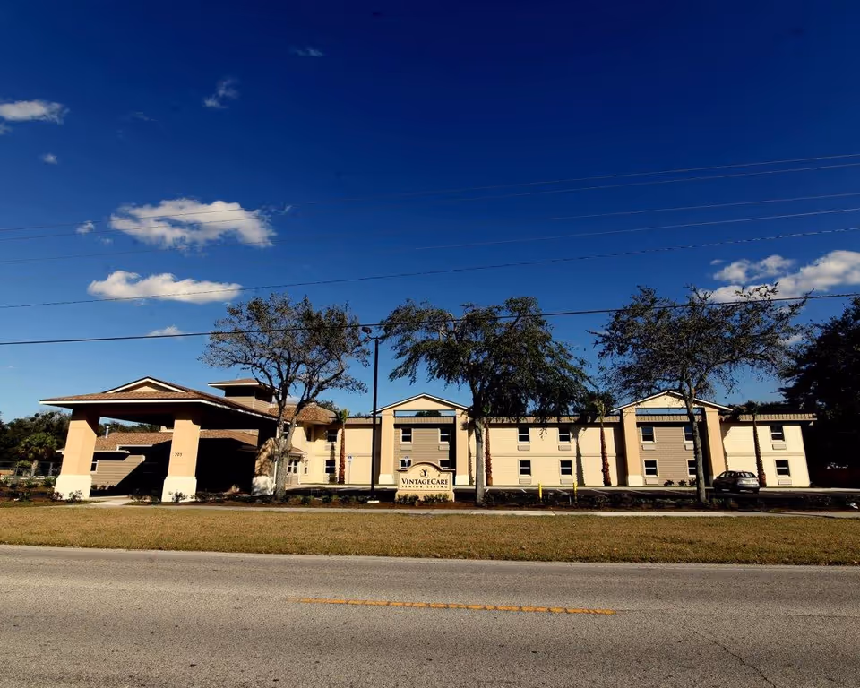 Front view of Vintage Care of Palatka senior living facility with palm trees.