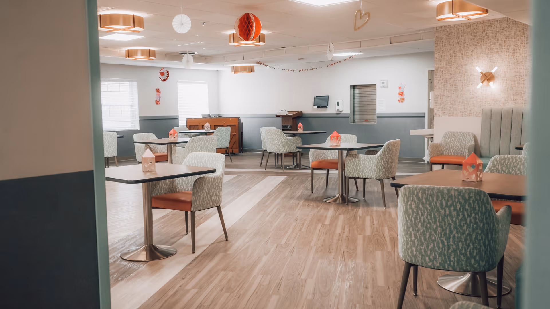 Spacious, well-lit dining room with multiple small tables and upholstered chairs and soft decor.