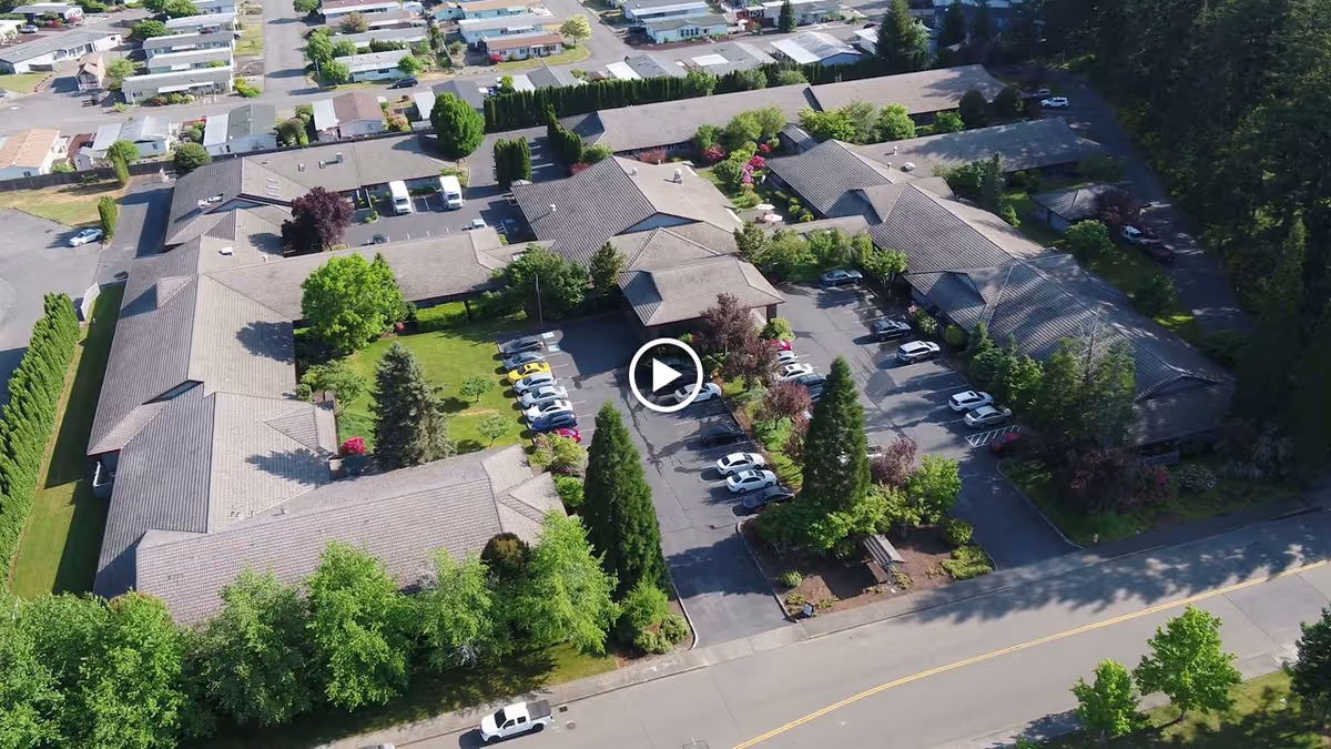 Aerial view of Alpine Way Continuing Care Community showing connected single-story buildings, a central parking lot and landscaped courtyards.