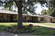 Lutheran Village exterior: single-story building with a manicured lawn and mature trees.
