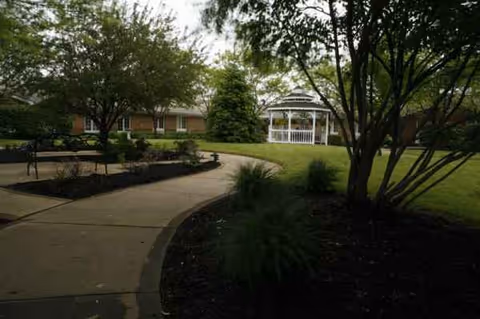 Outdoor courtyard at Cranberry Park at Pickaway Manor, curved walkway, benches, trees, and a white gazebo.