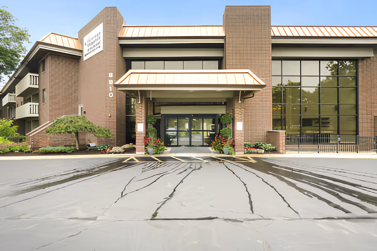 Front exterior view of King's Reserve College Park building with a covered entrance, large windows, and surrounding greenery.