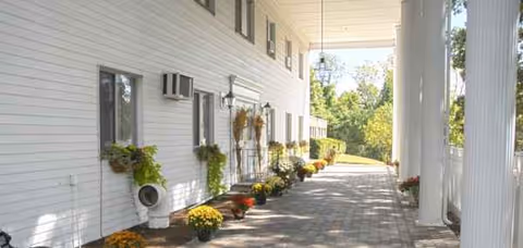 White exterior corridor of Pine Knoll Nursing Center with potted flowers along the walkway