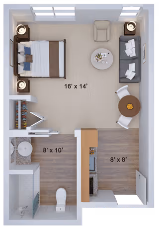 Top-down view of a senior living facility studio apartment floor plan at CareOne at Sharon, showing a combined living and sleeping area with a bed, nightstands, armchair, sofa, coffee table, and dining table with chairs. The kitchen area includes appliances and cabinetry, and there is a separate bathroom with a toilet, sink, and shower. Dimensions of each area are labeled.