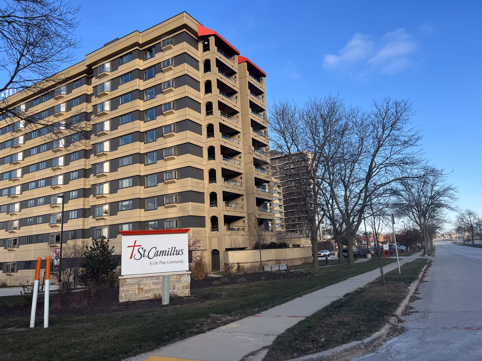 Exterior view of Camillus Court West senior living facility showing a multi-story building with a sign in front.
