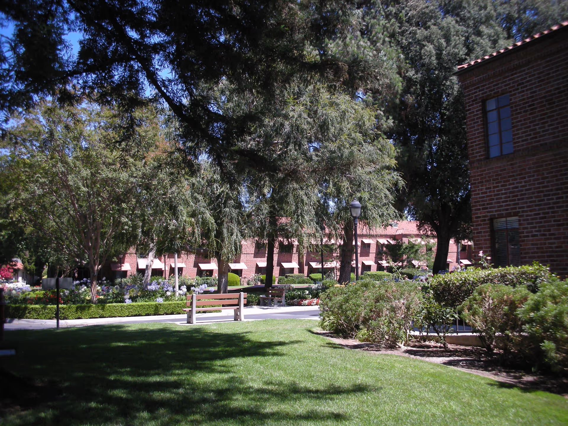 Courtyard lawn with benches, trees, and brick buildings of a retirement community.