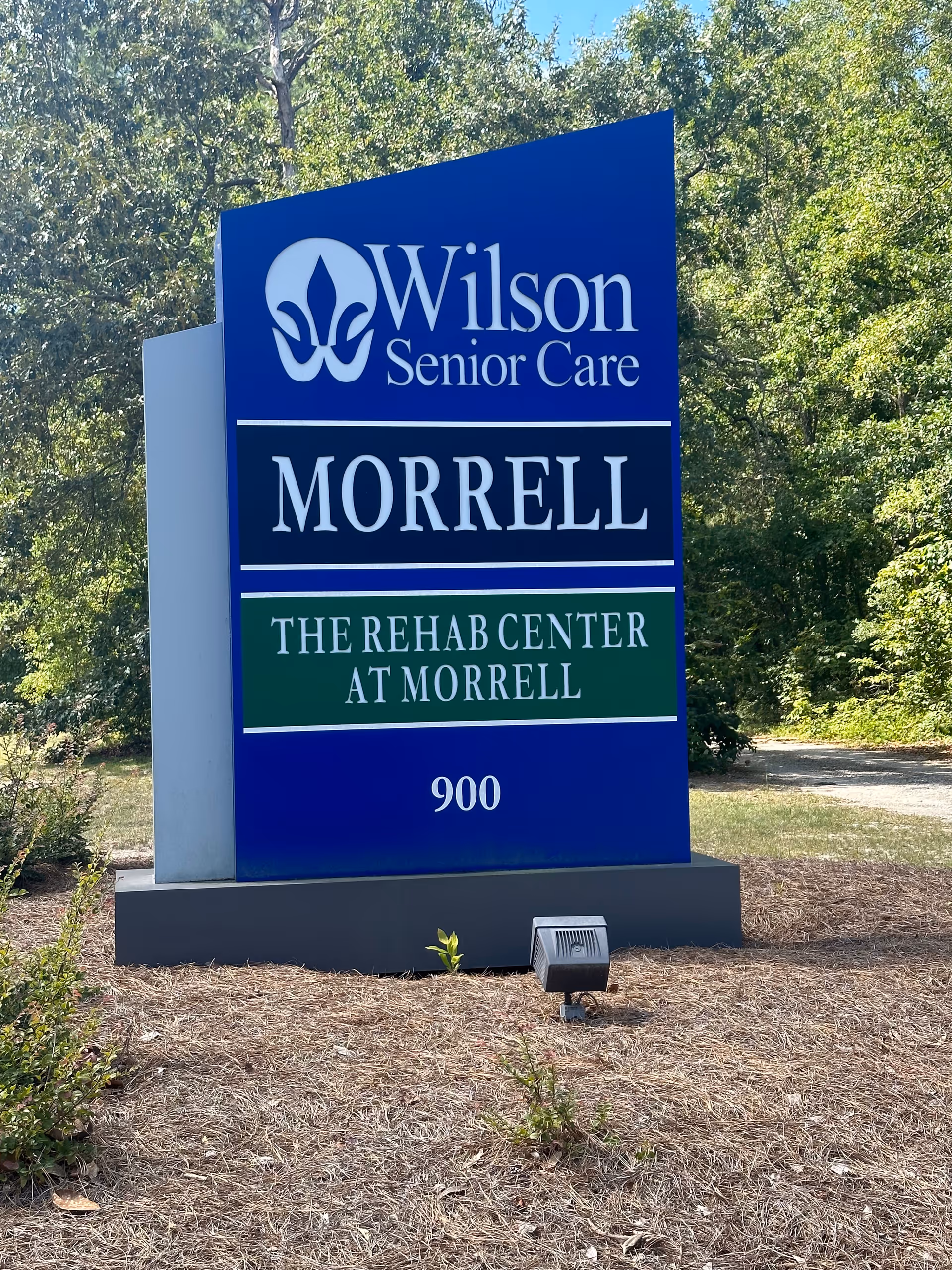 Outdoor sign for Wilson Senior Care Morrell, The Rehab Center at Morrell, located at 900, surrounded by trees and landscaping.