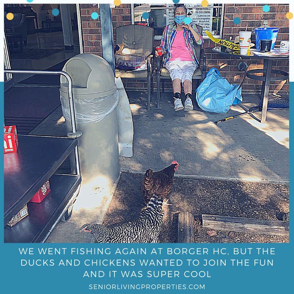 A masked person sits on an outdoor patio entrance while chickens roam in the foreground near a trash can and table.