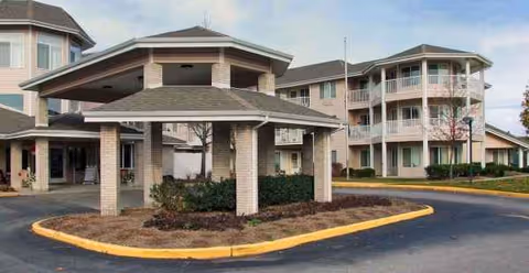 Exterior view of a senior living facility with a circular driveway and covered entrance.