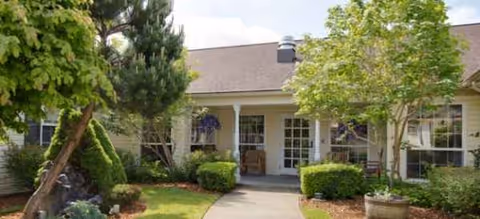 Exterior view of Brookdale Alderwood entrance with path, trees, and trimmed shrubs.