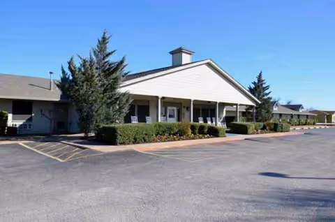 A single-story senior living facility exterior with a covered entrance and parking lot.