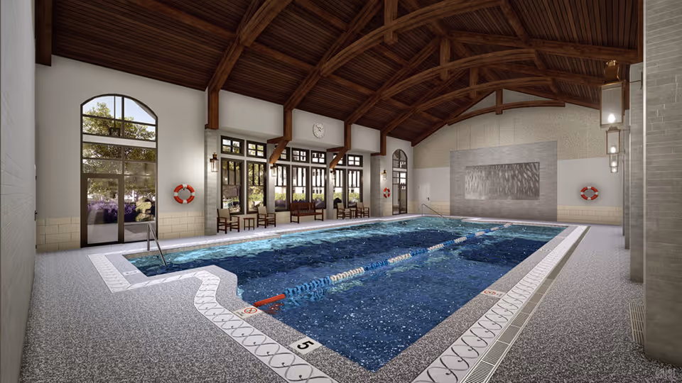Indoor lap pool with lane dividers, wooden vaulted ceiling, seating and large windows overlooking landscaping.