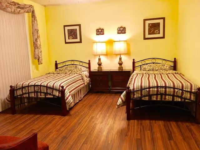 Two twin beds with striped covers sit side by side in a yellow bedroom.