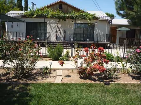 Single-story senior facility with a railed front walkway and vibrant flowering garden.