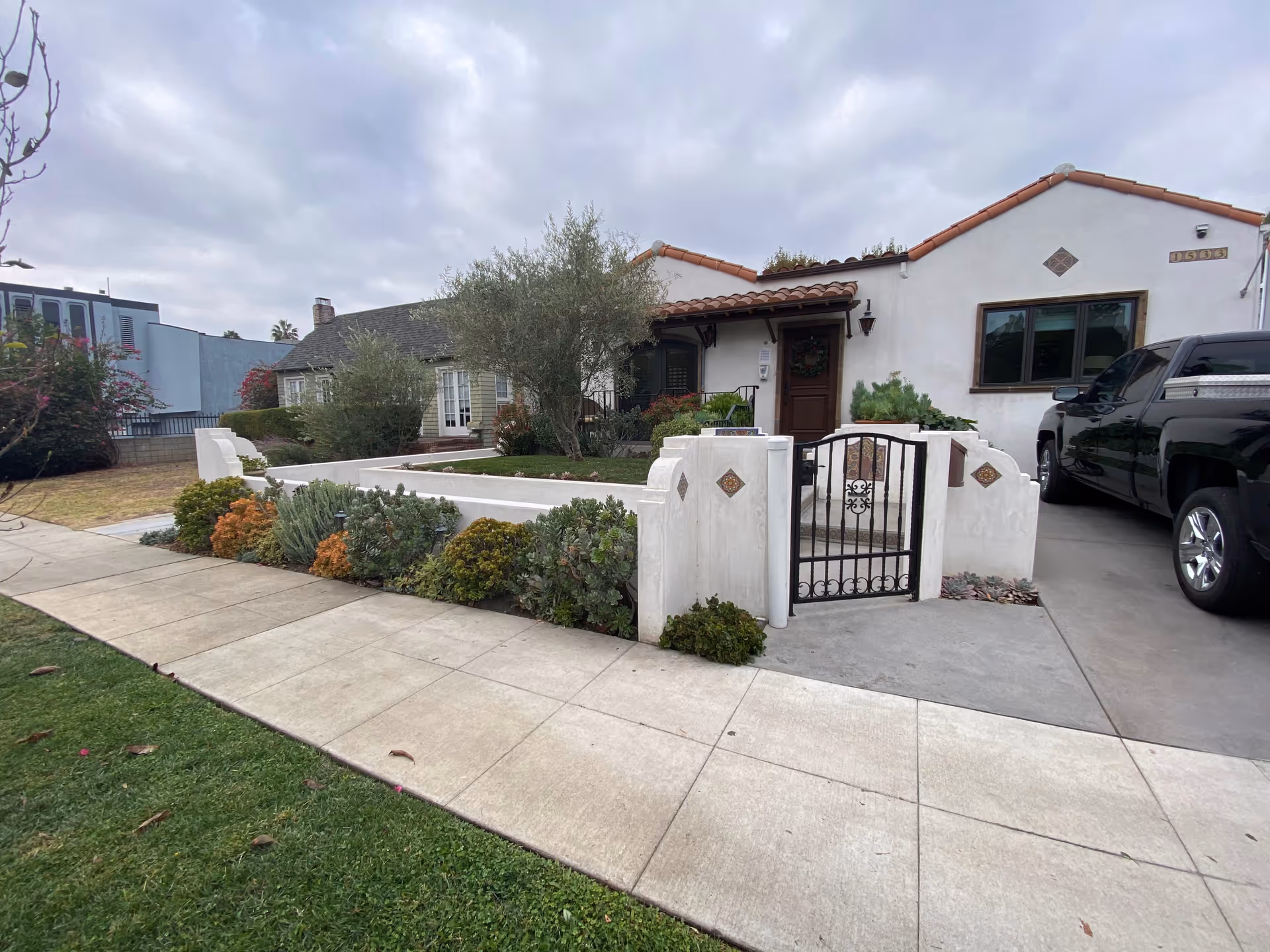 Front exterior of a single-story white stucco building with a decorative gate and landscaped border.