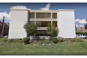 White three story senior care facility facade with landscaped front yard and shrubs.