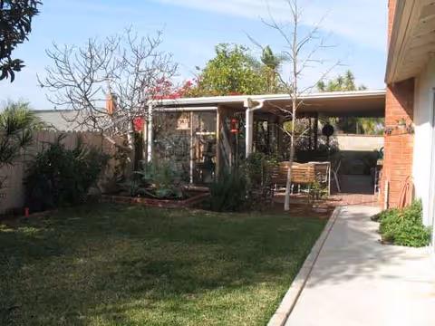 Outdoor courtyard with lawn, walkway, and a covered seating area.