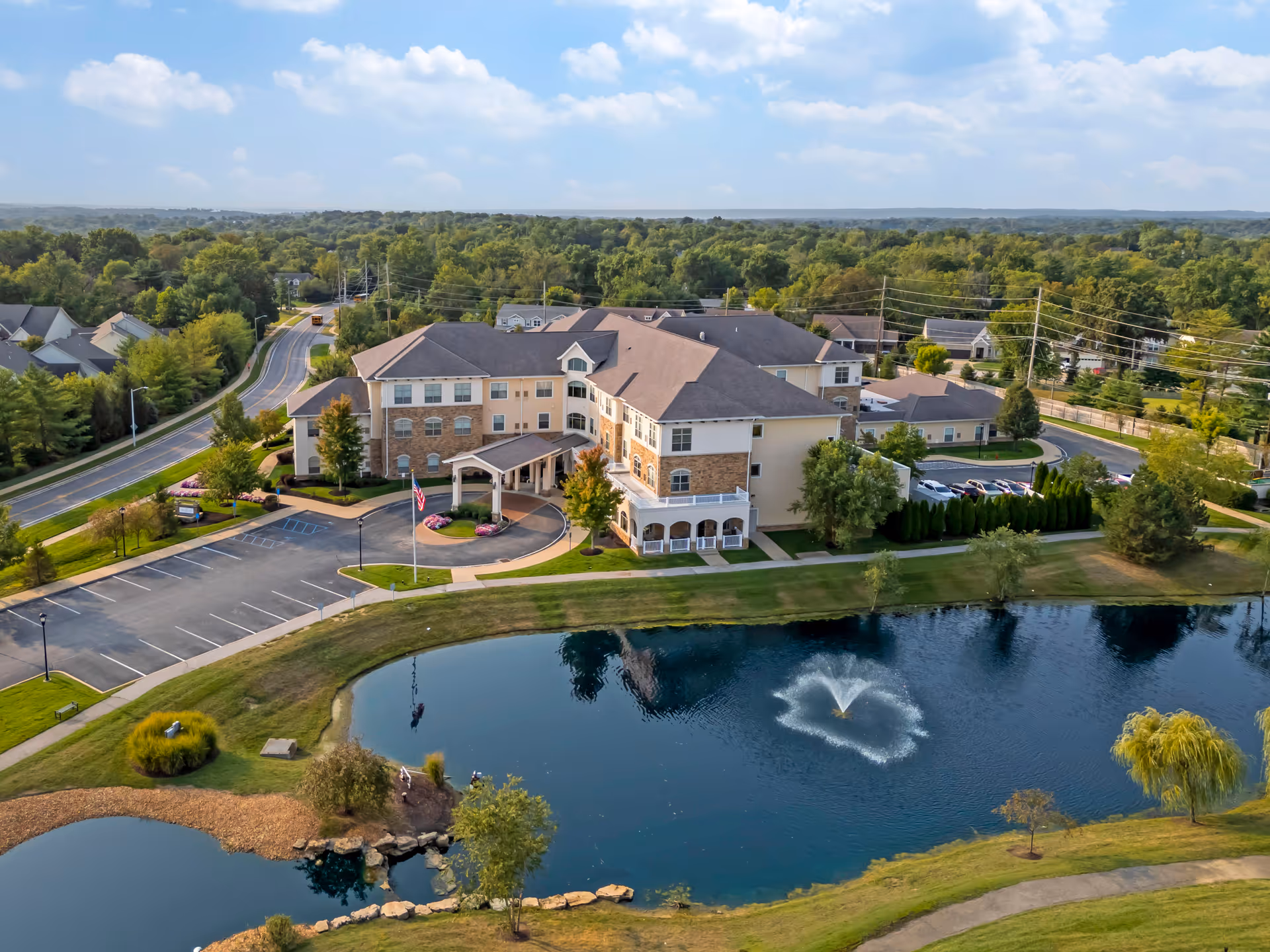 Aerial view of Brookdale West County building with parking and a pond.