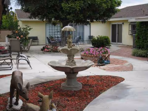 Outdoor courtyard with a fountain, seating, planters, and a building entrance in the background.