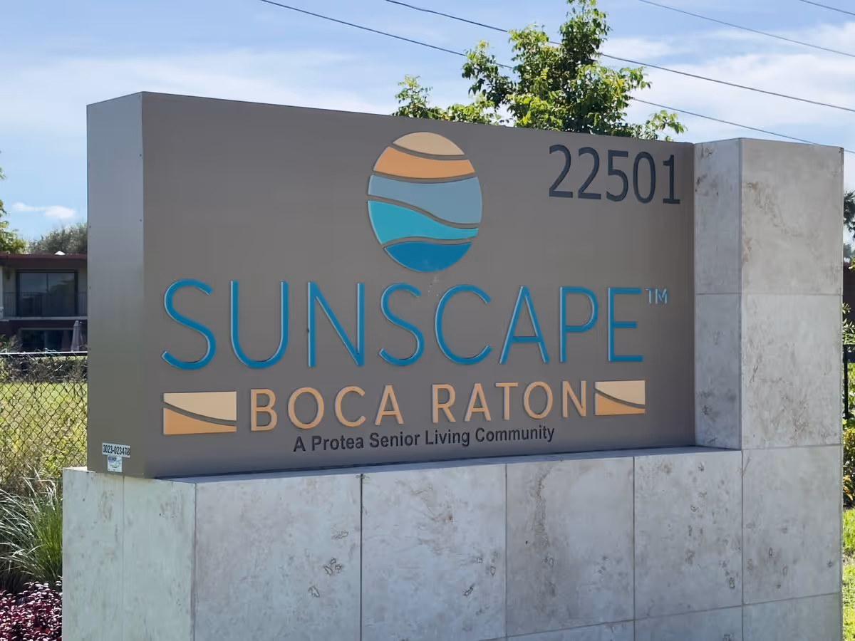 Entrance sign reading "Sunscape Boca Raton" with the address 22501 and logo mounted on a stone base.