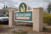 Outdoor stone entrance sign reading 'Life Care Center of Coeur d'Alene' with landscaping, a car, and a building in the background.