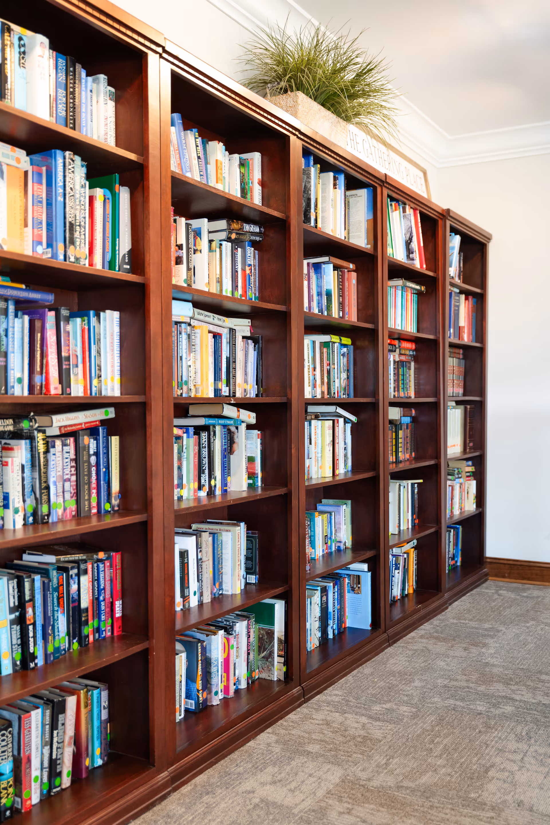 Tall wooden bookshelves filled with a variety of books in a community reading area.