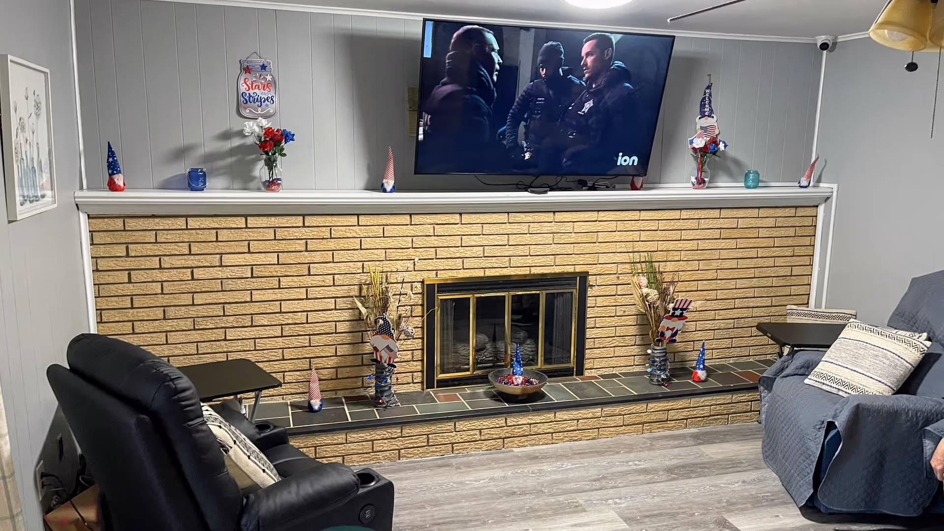 Cozy living room with brick fireplace, mounted TV, and seating in a senior living facility.