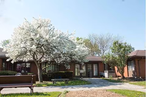 Exterior view of Seasons Nursing and Rehab building with blooming trees and benches.