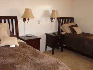 Two single beds with brown bedding and matching nightstands in a shared bedroom.