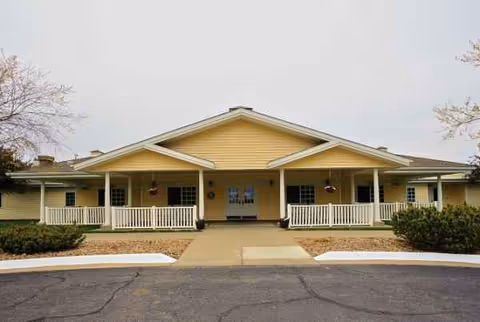 Front view of a single-story yellow memory care facility with a porch