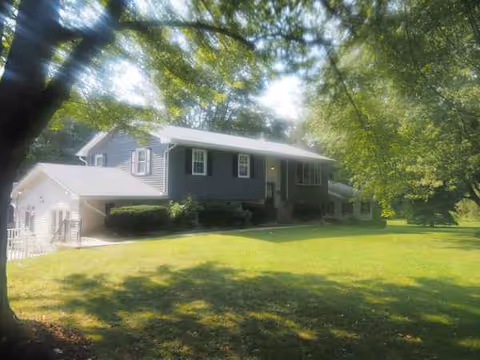 Blue two-story senior living house with green lawn and trees.