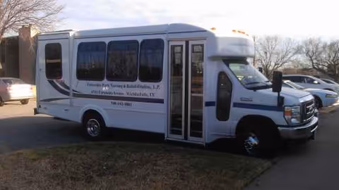 White shuttle bus for University Park Nursing & Rehabilitation parked outside a facility.