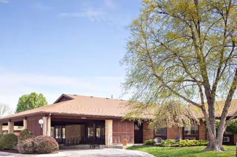 Brick single-story senior living facility exterior with entrance and landscaped grounds.