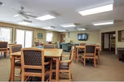Interior dining area with wooden tables, cushioned chairs, and bright ceiling lights.