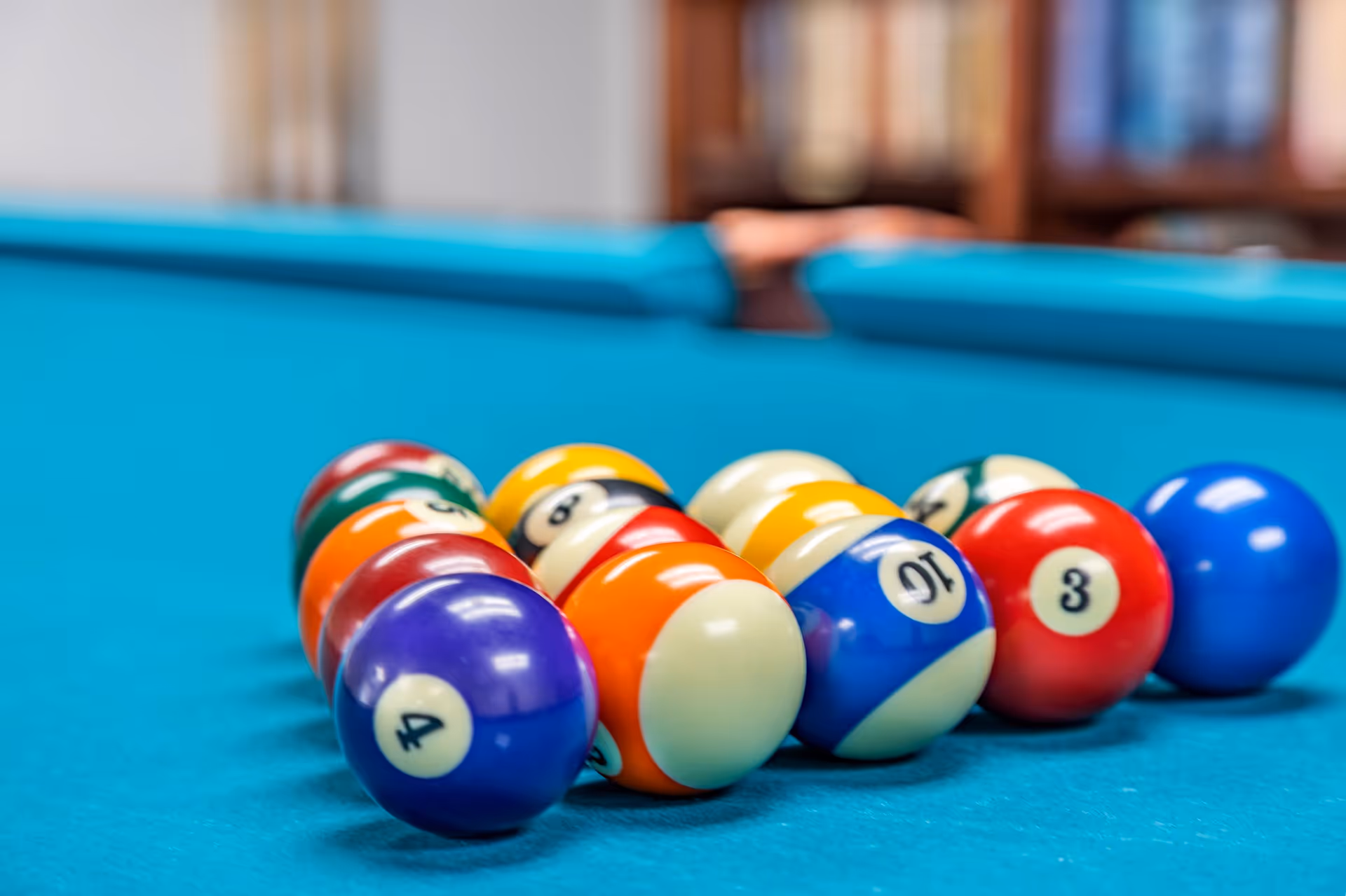 Close-up of a racked set of colorful billiard balls on a teal pool table.