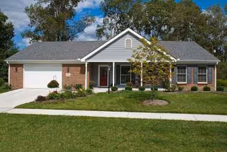 A single-story suburban-style building with a sloped roof, driveway, and neatly kept front lawn.