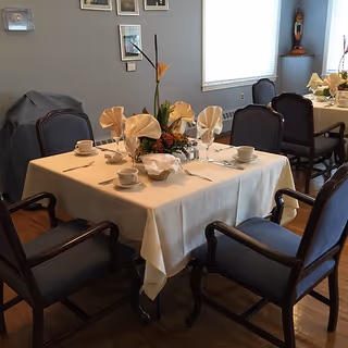 A dining table set with napkins and flowers in a senior living facility.