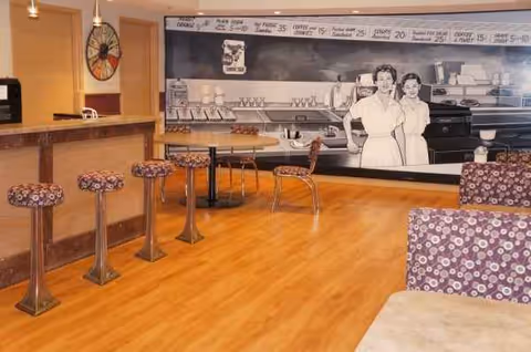 Retro diner-style dining area inside a senior living facility with bar counter and stools.