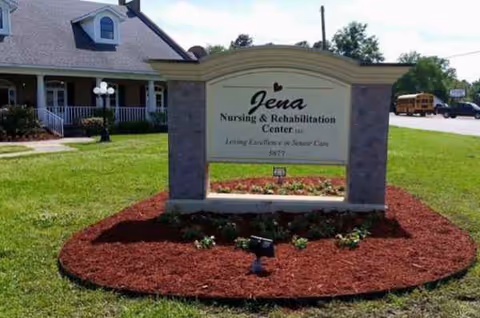 Exterior sign for Jena Nursing and Rehabilitation Center on a landscaped lawn with a building behind.