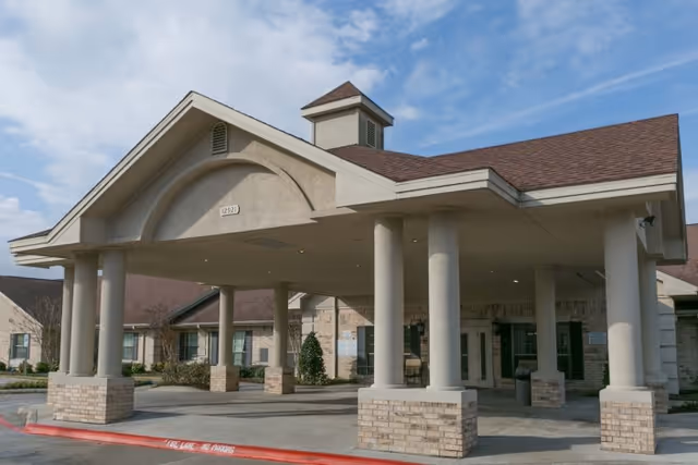 Front exterior view of Misty Willow Healthcare & Rehabilitation Center showing a covered entrance with large columns and a peaked roof under a partly cloudy sky.