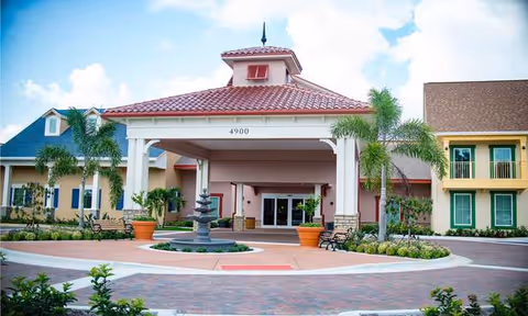 Exterior view of Symphony at Stuart entrance with canopy, palm trees, and landscaping