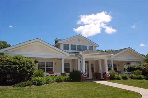 Front view of a senior living facility with a covered porch and bunting.