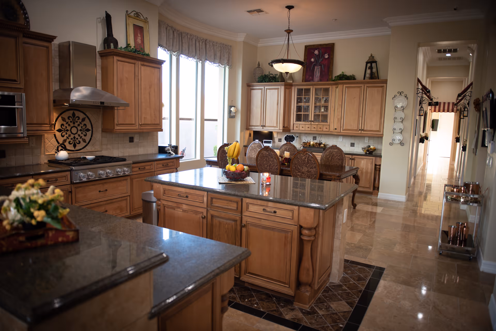 Large luxury kitchen with a central island, wooden cabinets, granite countertops, and a dining area in the background.