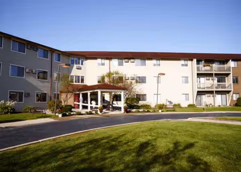 Exterior view of American House Grand Blanc senior living building with curved driveway and lawn